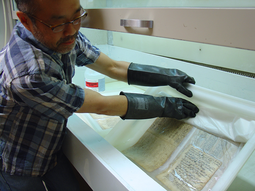 Manuscript record book leaves are washed in filtered water and ethanol to reduce discoloration and acidity of paper.